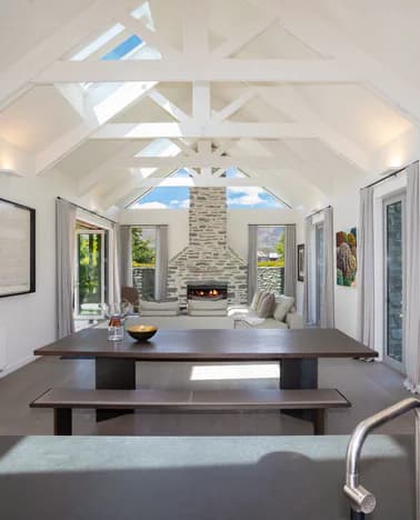 Open-plan dining area with exposed white beams and a stone fireplace